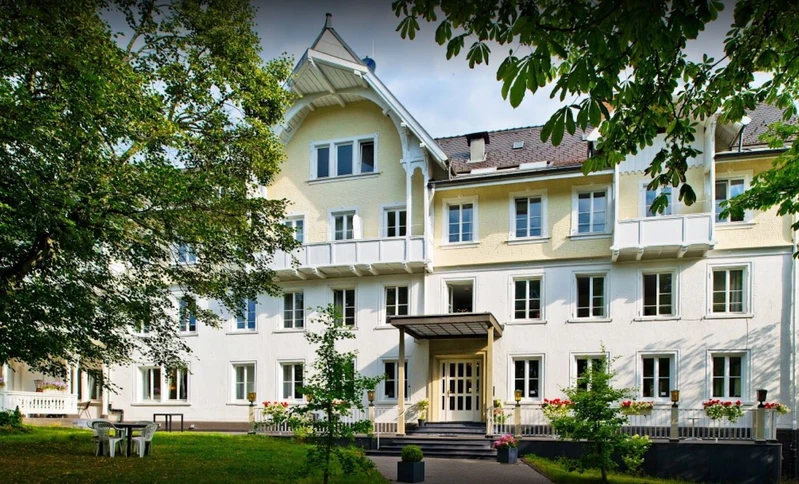 Au&szlig;enansicht der Privatklinik Friedenweiler der Oberberg Kliniken im Gr&uuml;nen mit blauem Himmel